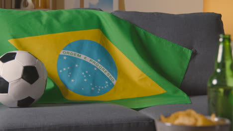 Flag-Of-Brazil-Draped-Over-Sofa-At-Home-With-Football-Ready-For-Match-On-TV-1