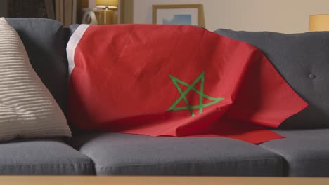 Flag-Of-Morocco-Draped-Over-Sofa-At-Home-Ready-For-Match-On-TV