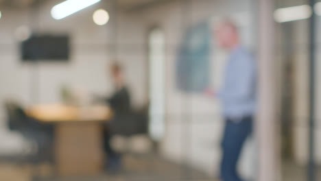 Defocused-Background-Shot-Of-Businesspeople-Working-At-Desk-In-Office-And-Talking-On-Phone-1