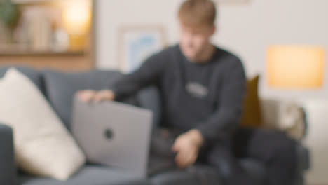 Defocused-Shot-Of-College-Student-Working-On-Laptop-At-Home