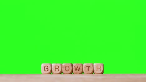 Business-Concept-Wooden-Letter-Cubes-Or-Dice-Spelling-Growth-Against-Green-Screen
