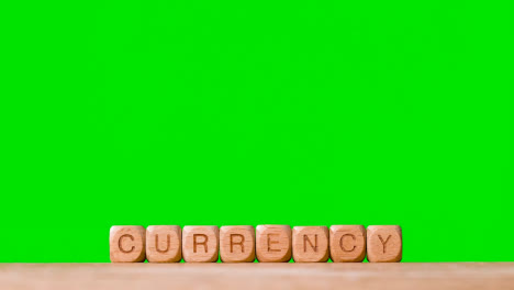 Business-Concept-Wooden-Letter-Cubes-Or-Dice-Spelling-Currency-Against-Green-Screen