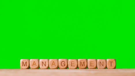 Business-Concept-Wooden-Letter-Cubes-Or-Dice-Spelling-Management-Against-Green-Screen
