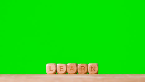 Education-Concept-Shot-With-Wooden-Letter-Cubes-Or-Dice-Spelling-Learn-Against-Green-Screen