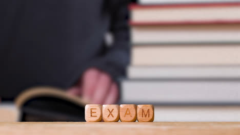 Education-Concept-Shot-With-Wooden-Letter-Cubes-Or-Dice-Spelling-Test-With-Person-Reading-Book-In-Library