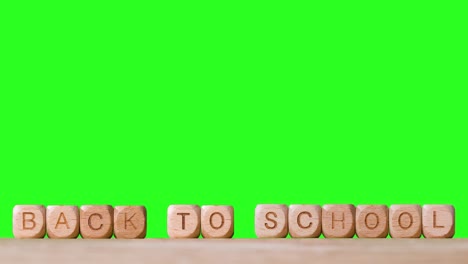 Education-Concept-With-Wooden-Letter-Cubes-Or-Dice-Spelling-Back-To-School-Against-Green-Screen-Background