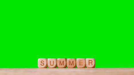 Concept-With-Wooden-Letter-Cubes-Or-Dice-Spelling-Summer-Against-Green-Screen-Background