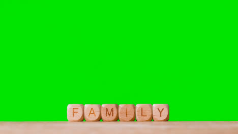 Concept-With-Wooden-Letter-Cubes-Or-Dice-Spelling-Family-Against-Green-Screen