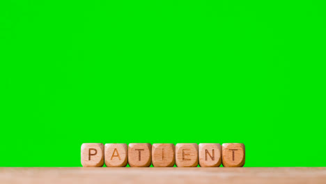 Medical-Concept-With-Wooden-Letter-Cubes-Or-Dice-Spelling-Patient-Against-Green-Screen-Background