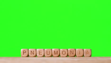 Medical-Concept-With-Wooden-Letter-Cubes-Or-Dice-Spelling-Pneumonia-Against-Green-Screen-Background