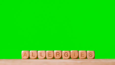 Medical-Concept-With-Wooden-Letter-Cubes-Or-Dice-Spelling-Allergies-Against-Green-Screen-Background