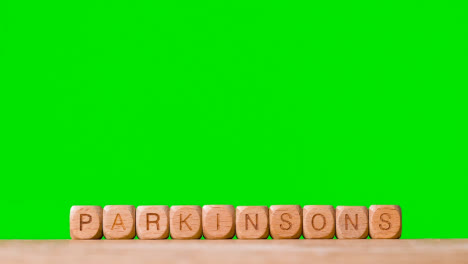 Medical-Concept-With-Wooden-Letter-Cubes-Or-Dice-Spelling-Parkinson's-Against-Green-Screen