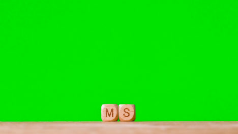 Medical-Concept-With-Wooden-Letter-Cubes-Or-Dice-Spelling-MS-Against-Green-Screen