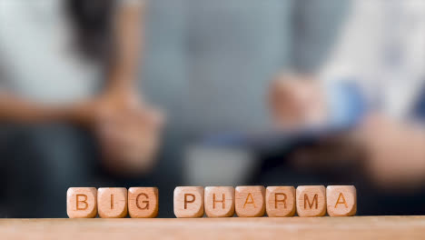 Medizinisches-Konzept-Mit-Holzbuchstabenwürfeln-Oder-Würfeln,-Die-Big-Pharma-Buchstabieren,-Vor-Dem-Hintergrund-Des-Arztes,-Der-Mit-Dem-Patienten-Spricht