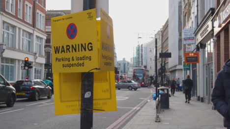 Typical-Busy-London-Street-With-Pedestrians-And-Traffic-And-Parking-Suspension-Notice