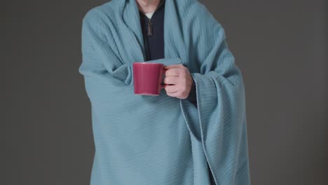 Close-Up-Of-Person-Wearing-Blanket-With-Hot-Drink-Trying-To-Keep-Warm-In-Energy-Crisis