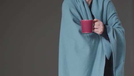 Close-Up-Of-Person-Wearing-Blanket-With-Hot-Drink-Trying-To-Keep-Warm-In-Energy-Crisis-1