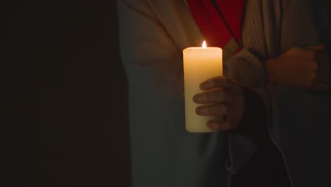 Close-Up-Of-Person-Wrapped-In-Blanket-Holding-Candle-To-Save-Electricity