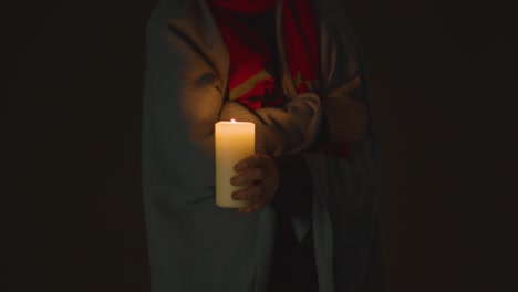 Close-Up-Of-Person-Wrapped-In-Blanket-Holding-Candle-To-Save-Electricity-2
