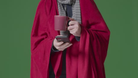 Close-Up-Of-Person-Wearing-Blanket-With-Hot-Drink-Using-Mobile-Phone-Trying-To-Keep-Warm-In-Energy-Crisis-5
