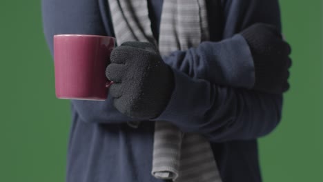 Nahaufnahme-Einer-Person-Mit-Handschuhen-Und-Schal-Mit-Heißem-Getränk,-Die-Versucht,-Sich-In-Der-Energiekrise-Warm-Zu-Halten