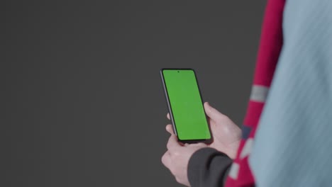 Close-Up-Of-Cold-Person-Wearing-Blanket-Holding-Green-Screen-Mobile-Phone-Trying-To-Keep-Warm-In-Energy-Crisis-1