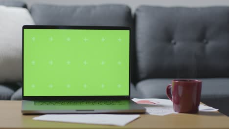 Laptop-Mit-Grünem-Bildschirm-Auf-Dem-Tisch-Zu-Hause,-Bedeckt-Mit-Rechnungen-In-Der-Lebenshaltungskrise