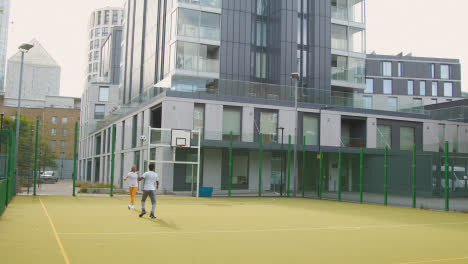 Künstlicher-Fußballplatz-Im-Städtischen-Stadtgebiet-Mit-Jungen-Paaren,-Die-Fußball-Treten