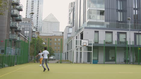 Artificial-Soccer-Pitch-In-Urban-City-Area-With-Young-Couple-Kicking-Football-
