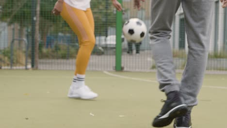 Close-Up-Of-Artificial-Soccer-Pitch-In-Urban-City-Area-With-Young-Couple-Kicking-Football-