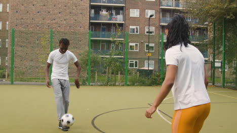 Artificial-Soccer-Pitch-In-Urban-City-Area-With-Young-Couple-Kicking-Football-4
