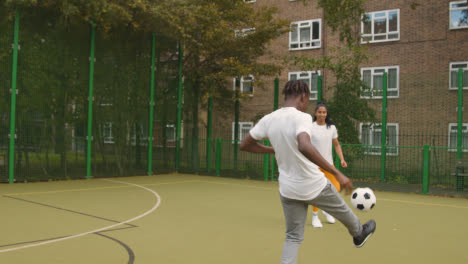 Artificial-Soccer-Pitch-In-Urban-City-Area-With-Young-Couple-Kicking-Football-5
