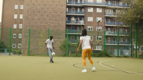 Artificial-Soccer-Pitch-In-Urban-City-Area-With-Young-Couple-Kicking-Football-6