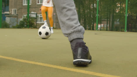 Junges-Paar-Kickt-Fußball-Auf-Künstlichem-Fußballplatz-Im-Urbanen-Stadtgebiet-2