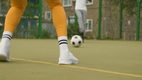 Close-Up-Of-Artificial-Soccer-Pitch-In-Urban-City-Area-With-Young-Couple-Kicking-Football-2