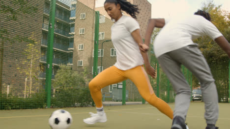 Young-Woman-Player-Dribbling-Football-On-Artificial-Soccer-Pitch-In-Urban-City-Area-3