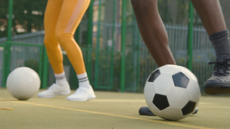 Close-Up-Of-Players-Practising-Ball-Control-On-Artificial-Soccer-Pitch-In-Urban-City-Area-
