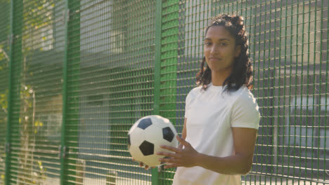 Portrait-Of-Young-Woman-Holding-Football-On-Artificial-Soccer-Pitch-In-Urban-City-Area-4