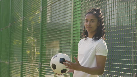 Portrait-Of-Young-Woman-Holding-Football-On-Artificial-Soccer-Pitch-In-Urban-City-Area-4