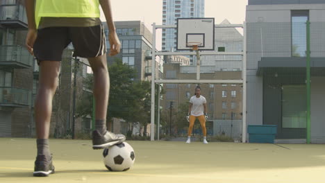 Young-Soccer-Players-Shooting-And-Saving-Shot-On-Goal-On-Artificial-Football-Pitch-In-Urban-City-Area-
