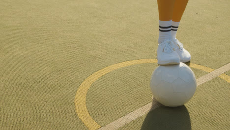 Close-Up-Of-Young-Woman-Placing-Football-On-Centre-Circle-Of-Artificial-Soccer-Pitch-In-Urban-City-For-Kick-Off