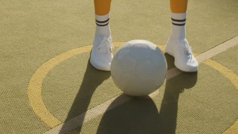Close-Up-Of-Young-Woman-Placing-Football-On-Centre-Circle-Of-Artificial-Soccer-Pitch-In-Urban-City-For-Kick-Off-1