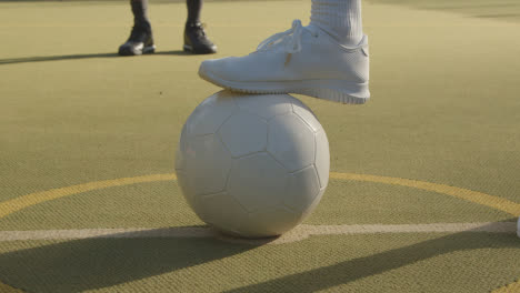 Close-Up-Of-Young-Woman-Placing-Football-On-Centre-Circle-Of-Artificial-Soccer-Pitch-In-Urban-City-For-Kick-Off-3