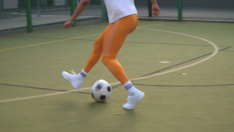 Close-Up-Of-Players-Kicking-And-Passing-Football-On-Artificial-Soccer-Pitch-In-Urban-City-Area-