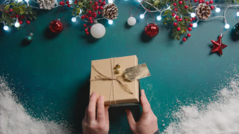 Überkopfaufnahme-Einer-Person,-Die-Ein-In-Geschenk-Verpacktes-Weihnachtsgeschenk-Mit-Festlichem-Hintergrund-öffnet-1