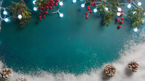 Overhead-Weihnachtshintergrund-Mit-Schnee-Beleuchtet-Stechpalme-Und-Tannenzapfen