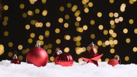 Christmas-Background-With-Snow-Tree-Decorations-And-Tree-Lights-In-Background