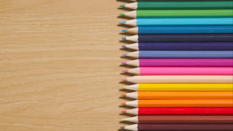 Lápices-De-Colores-Dispuestos-En-Una-Línea-Sobre-Fondo-De-Madera