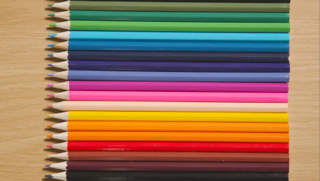 Lápices-De-Colores-Dispuestos-En-Una-Línea-Sobre-Fondo-De-Madera-1