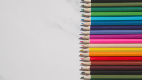 Lápices-De-Colores-Dispuestos-En-Una-Línea-Sobre-Fondo-De-Mármol-Blanco-1